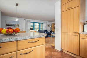 A kitchen with wooden cabinets, a granite countertop, and a fruit bowl. - 11/T6 holiday home park “Freesenbruch” (Zingst (Ostseeheilbad))