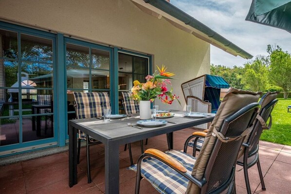 An outdoor dining area with a table set for two, chairs, and a flower vase. - 11/T6 holiday home park “Freesenbruch” (Zingst (Ostseeheilbad))