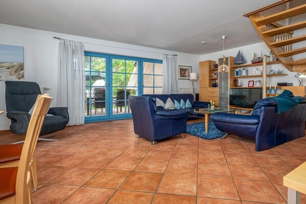 Uma sala de estar com sofá, televisão e escada de madeira.