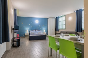 Quarto moderno com cama, mesas de cabeceira e televisão.