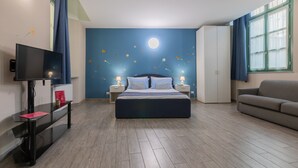 A bedroom with a bed, a TV, a desk, a wardrobe, and a sofa. - Housing Giulia - Apartment 8 by Wonderful Italy (Turin)