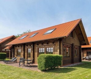 A log cabin with a sloped roof, a patio with seating, and a well-maintained lawn. - Holiday home in Sassnitz/Rügen with sauna (Sassnitz\/Rügen)