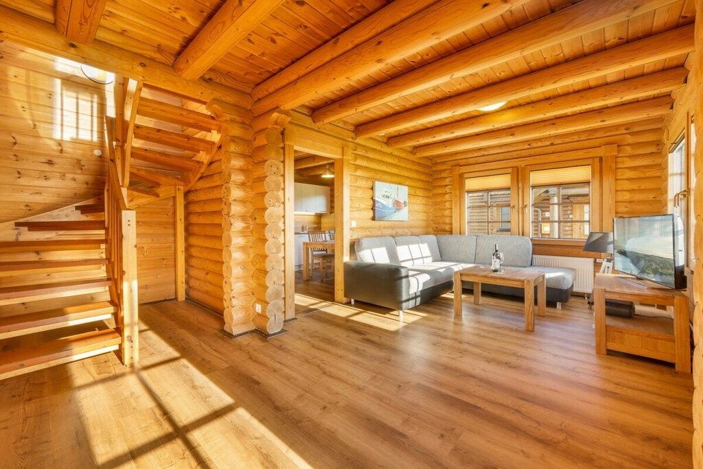 L’intérieur d’une cabane en rondins, avec un escalier, un canapé, une table basse et un téléviseur.