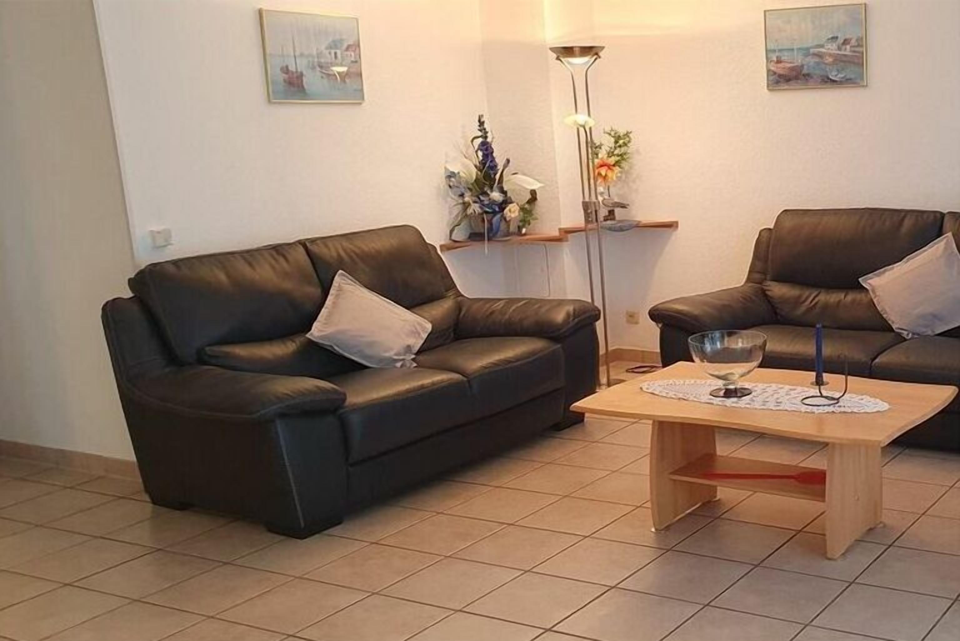 A living room with two black leather sofas, a wooden coffee table, and a floor lamp.