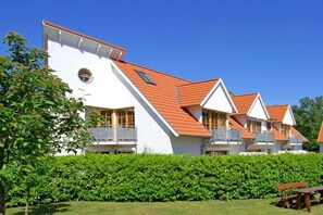 A row of white buildings with red roofs and balconies, surrounded by green hedges. - 4.6/T1 holiday home park “Freesenbruch” (Zingst (Ostseeheilbad))