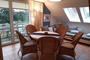 Ein Essbereich mit Korbstühlen, einem runden Tisch und Blick durch große Fenster.