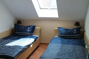 Ein kleiner, kompakter Raum mit zwei Einzelbetten, jeweils mit passendem Kopfkissen und Nachttisch.