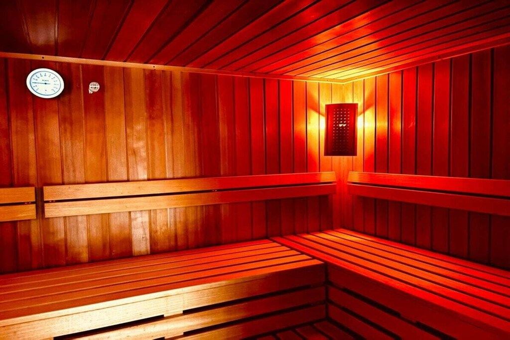 A sauna with wooden benches and a wall-mounted heater.