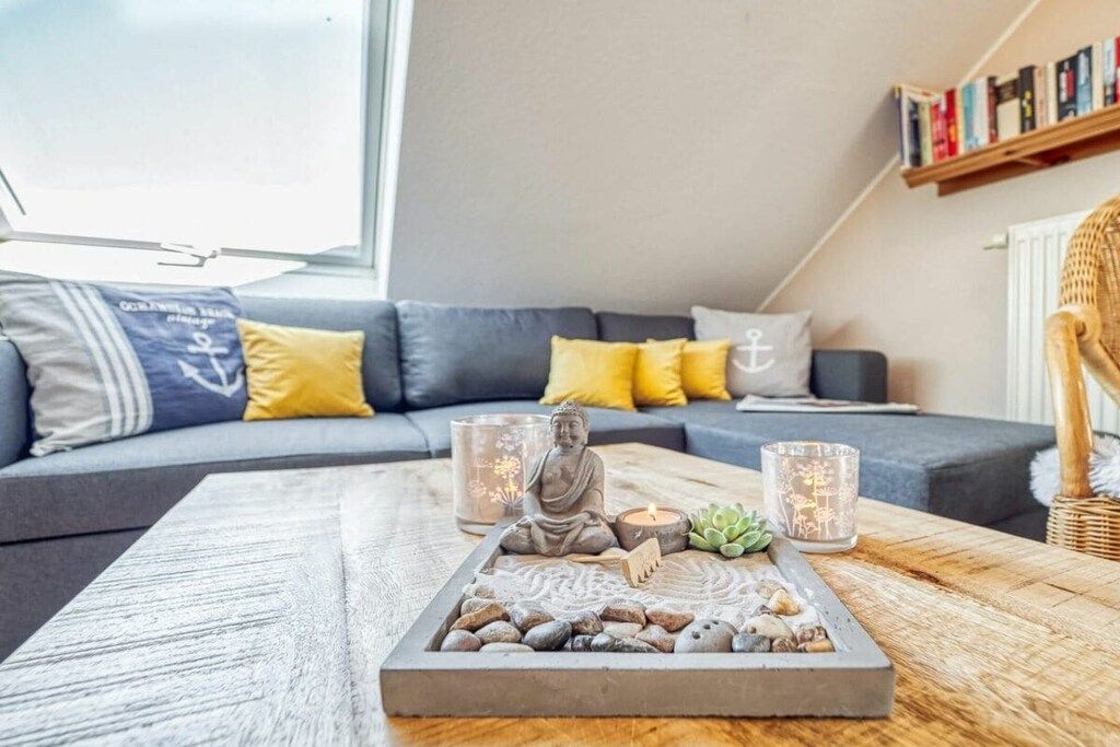 A modern living room with a grey sofa, yellow cushions, a wooden coffee table with a decorative tray, and two lit candles.