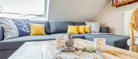 A modern living room with a grey sofa, yellow cushions, a wooden coffee table with a decorative tray, and two lit candles.