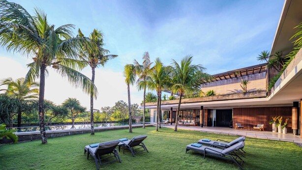 A modern outdoor area with a pool, lounge chairs, and palm trees. - Villa Babadan (Badung)