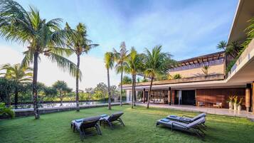 Un espacio exterior moderno con piscina, sillas de descanso y palmeras.