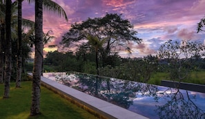 Una piscina con vistas despejadas a árboles y un cielo al atardecer.