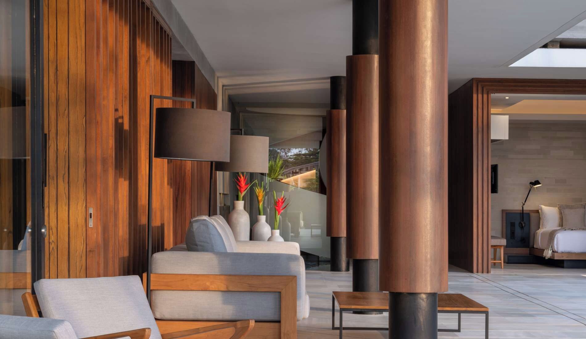 Interior moderno com sofá, mesa de centro e luminária. Painéis de madeira e uma janela grande.