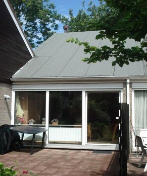 A covered patio with a sliding glass door, a table, and chairs. - Holiday home with 3 bedrooms (LB Zoutelande)