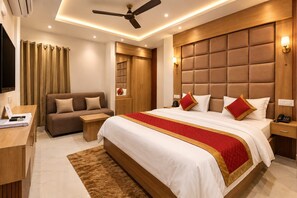 Una habitación de hotel con una cama grande, un sofá, un escritorio y un ventilador de techo.
