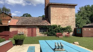 A brick building with a tiled roof, a wooden fence, and a picnic table with a sculpture. - Holiday home with 5 bedrooms (Trebel, Niedersachsen)