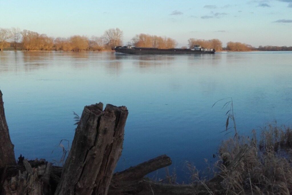 A calm river with a boat and a dock in the foreground.