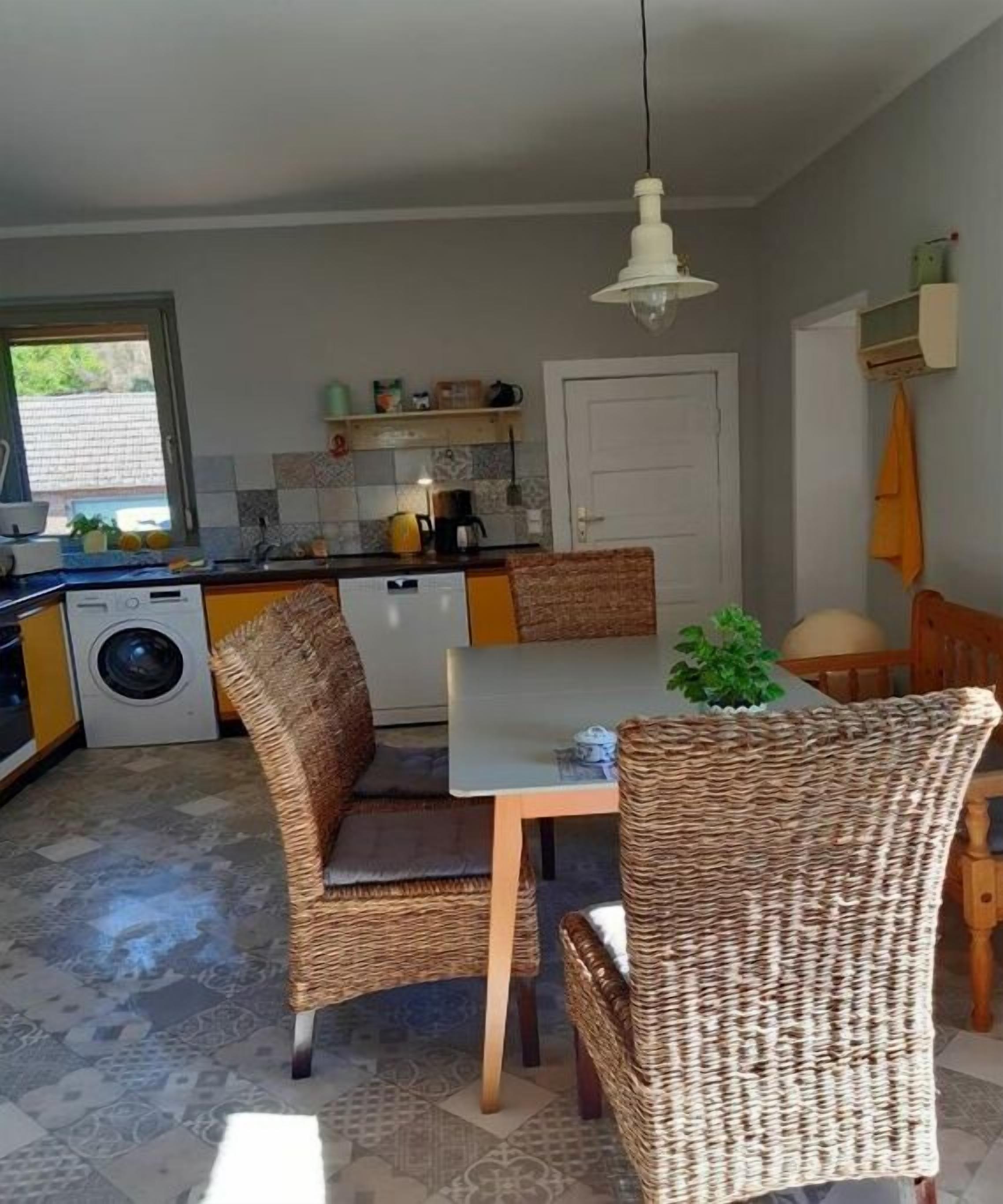 Una cocina con una mesa de comedor y sillas, lavadora, y una lámpara colgante.