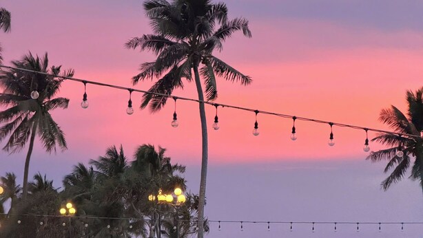 A beach setting with palm trees, a volleyball net, and a boat on the sand. - Amorii Hotel Phu Quoc (Phu Quoc)