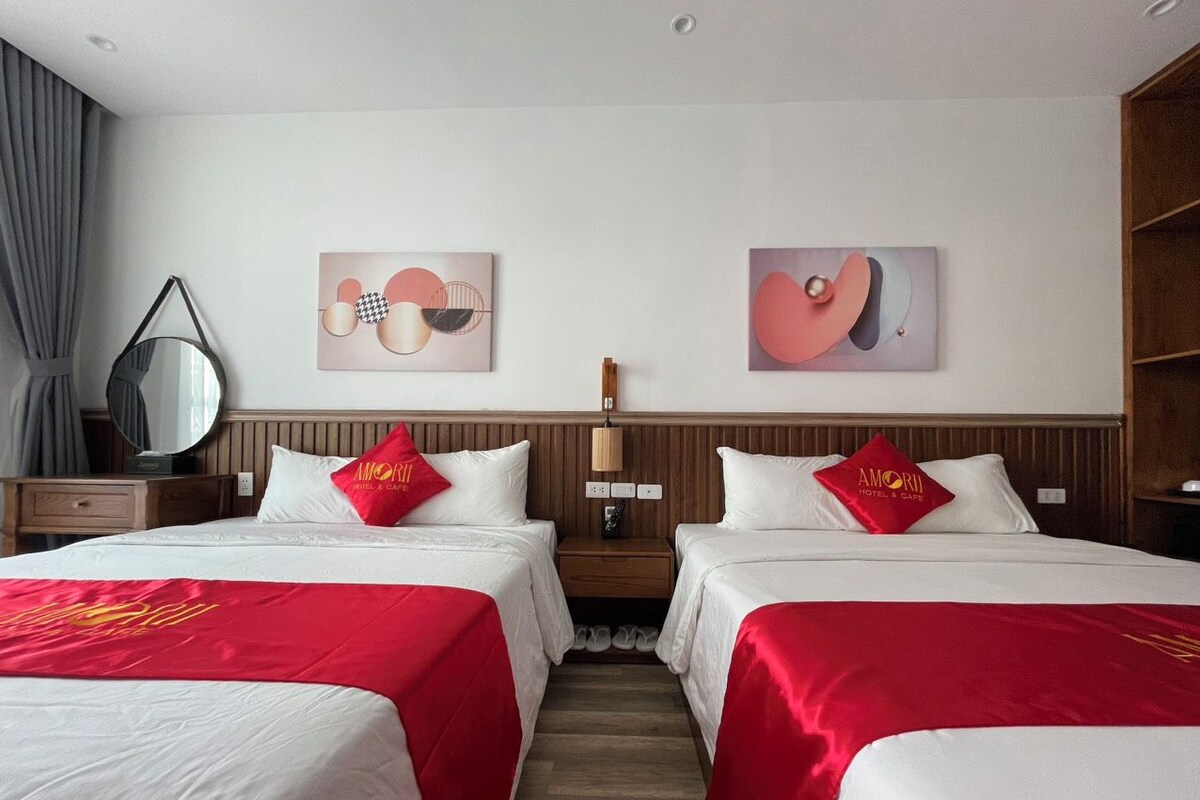 Et hotelværelse med to senge, et natbord, et spejl og kunst på væggene.