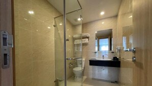 A modern bathroom with a glass shower enclosure, a toilet, and a sink with a mirror above. - Amorii Hotel Phu Quoc (Phu Quoc)