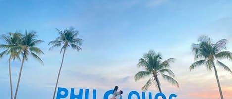 Escena de playa con palmeras y el texto 'PHU QUOC' escrito en la arena.