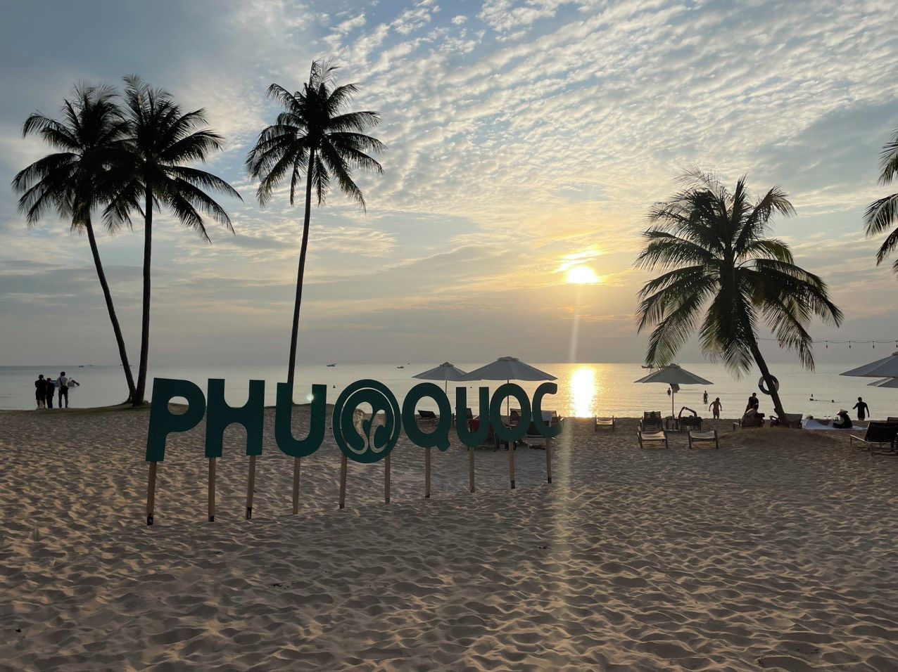 A beach with palm trees, sun, and the text 'PHUQUOC'.