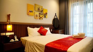 A hotel room with a bed, a nightstand, a lamp, a wall clock, and artwork. - Amorii Hotel Phu Quoc (Phu Quoc)