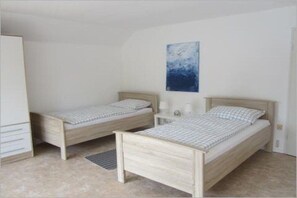 A bedroom with two single beds, a wardrobe, a bedside table with a lamp, and a painting on the wall. - Holiday home in Aurich with swimming pool (Aurich)