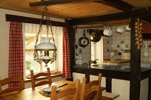 A rustic kitchen with wooden furniture, a hanging light fixture, and tiled backsplash. - Holiday home with 1 bedroom (Neuenkirchen)