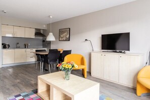 A modern living room with a dining area, a kitchen, and a television. - Apartment with 1 bedroom (Hollum Ameland)