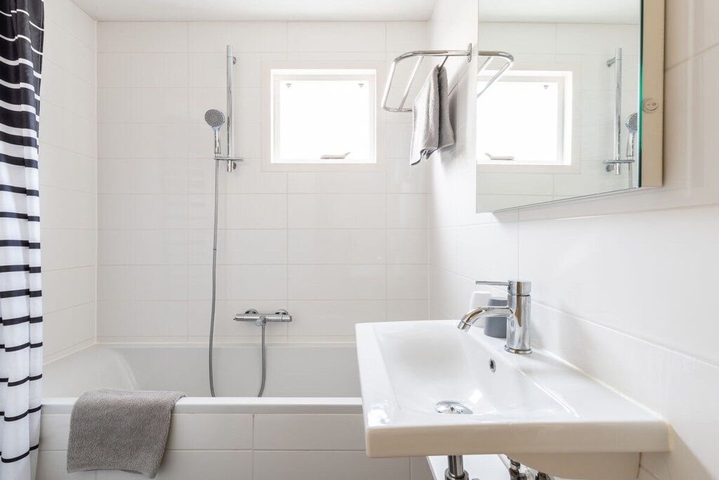 A bathroom with a bathtub, a shower, a sink, and a window.