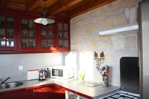 A kitchen with red cabinets, a white microwave, and a gas stove. - Chalet 'Le De Marie': Mountain View, Shared Terrace, and Wi-Fi (Foncine-le-Haut)