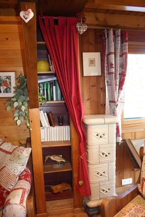 Ein gemütliches Zimmer mit Holzvertäfelung, einem Bücherregal, einem Kamin und einem Fenster mit Vorhängen.