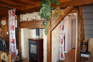Ein rustikaler Innenraum mit Kamin aus Stein, Holzbalken und gemusterten Vorhängen.