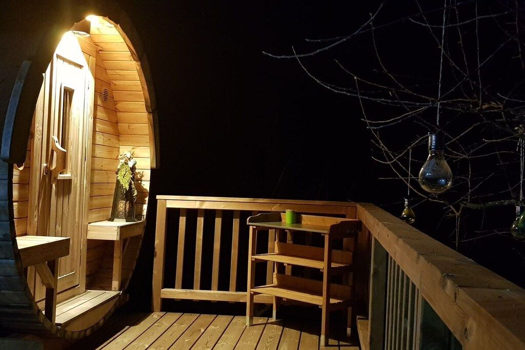 A wooden deck with a bench and a table, a small statue, and a hanging light fixture.