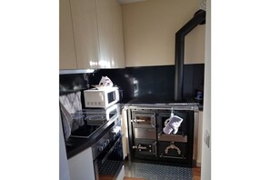 Eine kleine Küche mit Mikrowelle, Herd, Backofen und einer schwarzen Arbeitsplatte.