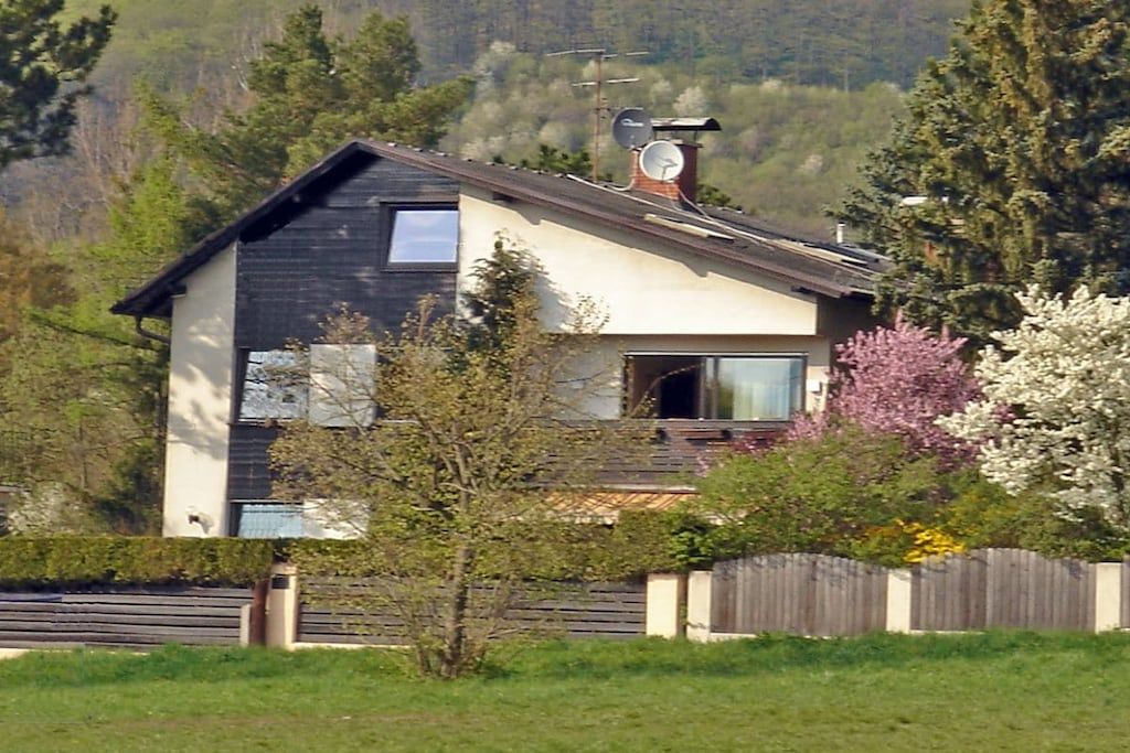 Una casa moderna de dos pisos con techo inclinado, antena parabólica y chimenea visible.