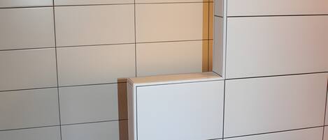 A bathroom with white tiled walls and a tiled floor.