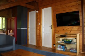 A living room with a television mounted on the wall, a sofa, a coffee table, and a fireplace with a Scrabble box on it. - Chalet "Le Cocon": Mountain View, Private Terrace & Wi-Fi (Foncine le Haut)