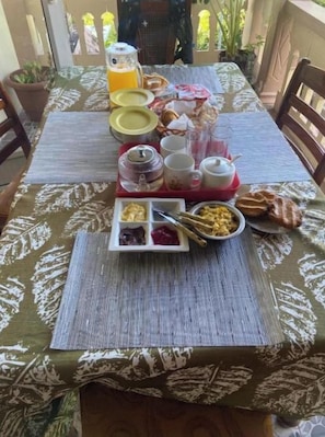 A table set with breakfast items including a pitcher, cups, plates, and a tray with food. - Henz & Sia Tourist Residence – Your Island Home in Rodrigues 🌴 (Piments Reposoir Rodrigues)