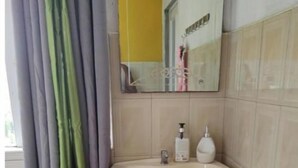 Un baño con lavamanos pedestal, un espejo y una bañera.