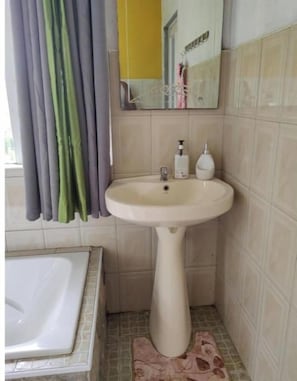 A bathroom with a pedestal sink, a mirror, and a bathtub. - Henz & Sia Tourist Residence – Your Island Home in Rodrigues 🌴 (Piments Reposoir Rodrigues)