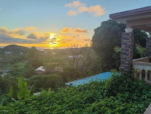 Un quartier résidentiel offrant une vue sur le coucher de soleil, qui se reflète sur un paysage vallonné.
