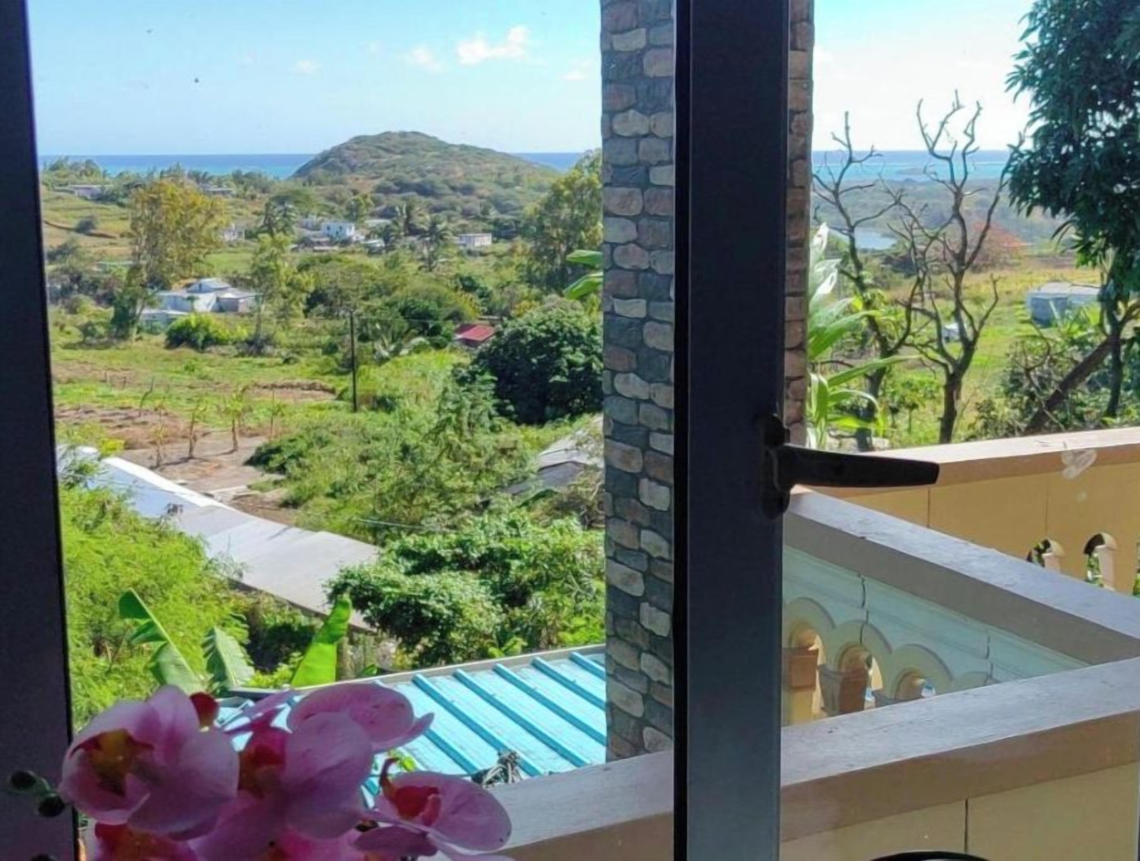 A balcony with a view of a green landscape and distant hills.