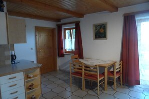 A room with a wooden ceiling, a table with chairs, a cabinet, and a window with curtains. - Holiday home with 3 bedrooms (St. Stefan ob Stainz)