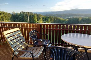 A balcony with a table and chairs, overlooking a forested landscape with mountains in the distance. - Holiday home with 3 bedrooms (St. Stefan ob Stainz)