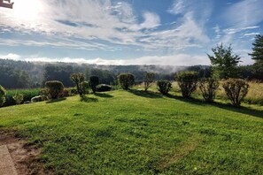 A grassy field with neatly trimmed bushes and trees, a clear sky, and a distant forested area. - Holiday home with 3 bedrooms (St. Stefan ob Stainz)