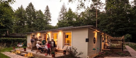 Une petite maison avec un porche, un espace salon extérieur et un jardin.